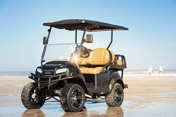 En Onward-golfvogn fra Club Car i Lifted-versionen er parkeret på en strand.