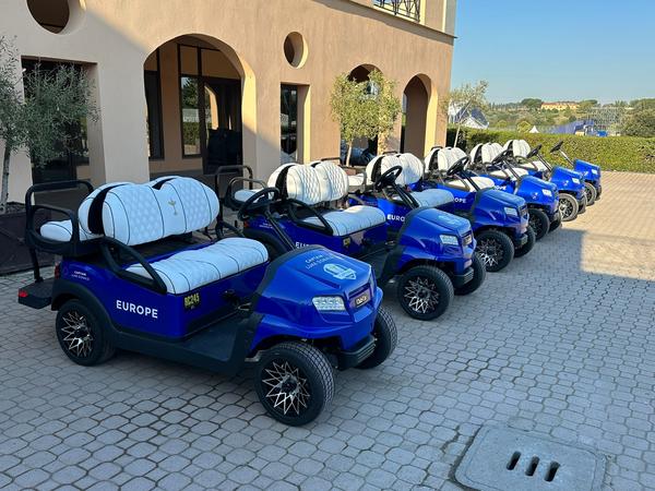 Holdvogne fra Team Europe parkeret foran klubhuset på Marco Simone Golf Course i Rom under Ryder Cup 2023.