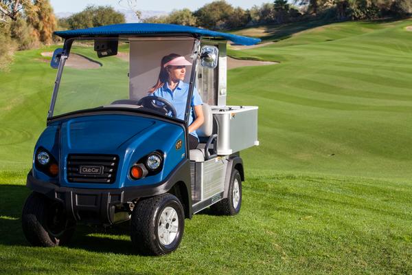 Ei Mini Food Truck steht auf einem Golfplatz. In dem Fahrzeug sitzt eine Frau, die auf Kundschaft wartet.